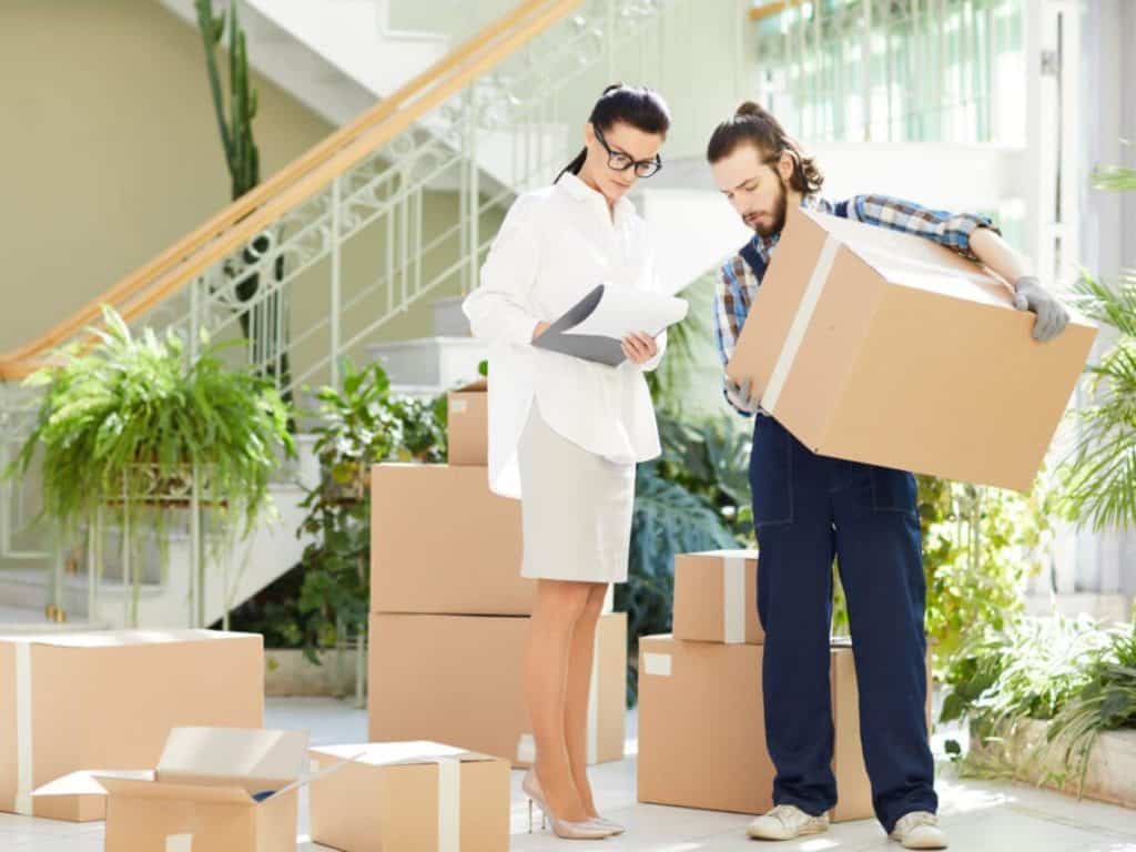 A woman is helping an employee who is moving boxes in an office setting