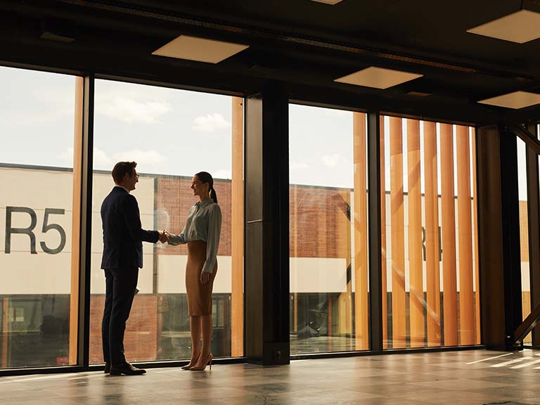 Two people shaking hands in office building (commercial real estate trends)