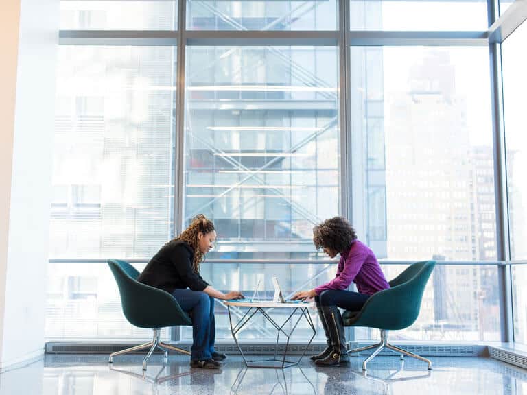 Two women work on laptops in hybrid work environment